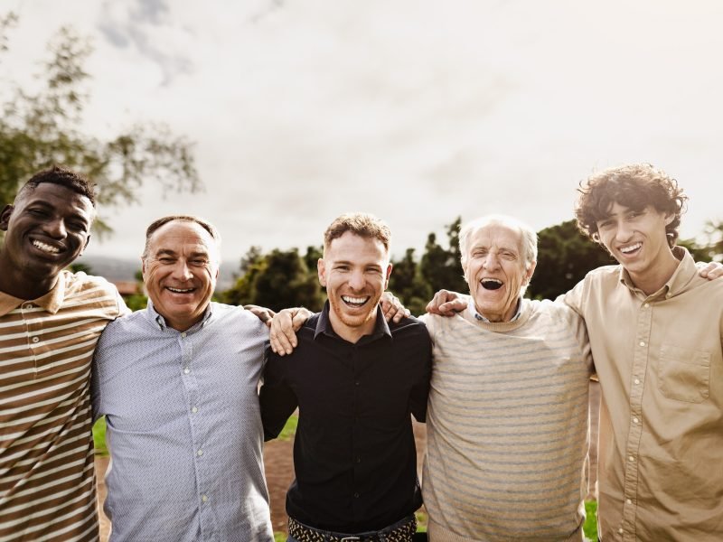 Happy multigenerational group of men having fun smiling in front of camera at park